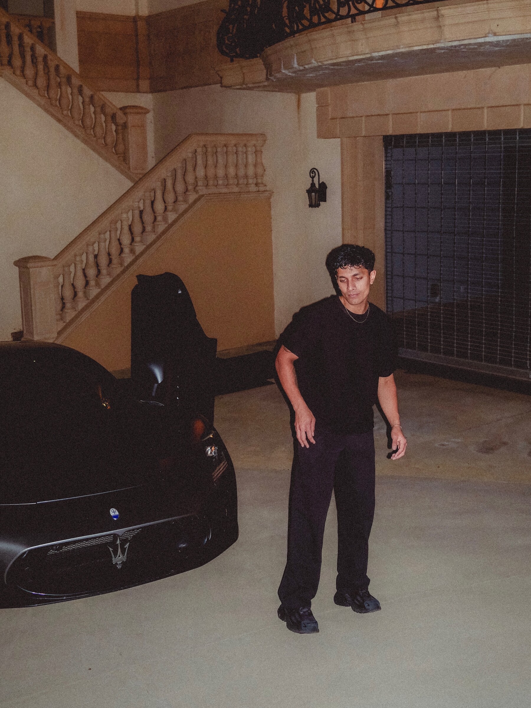 Aryan Mahajan wearing black beside a Maserati MC20 at night