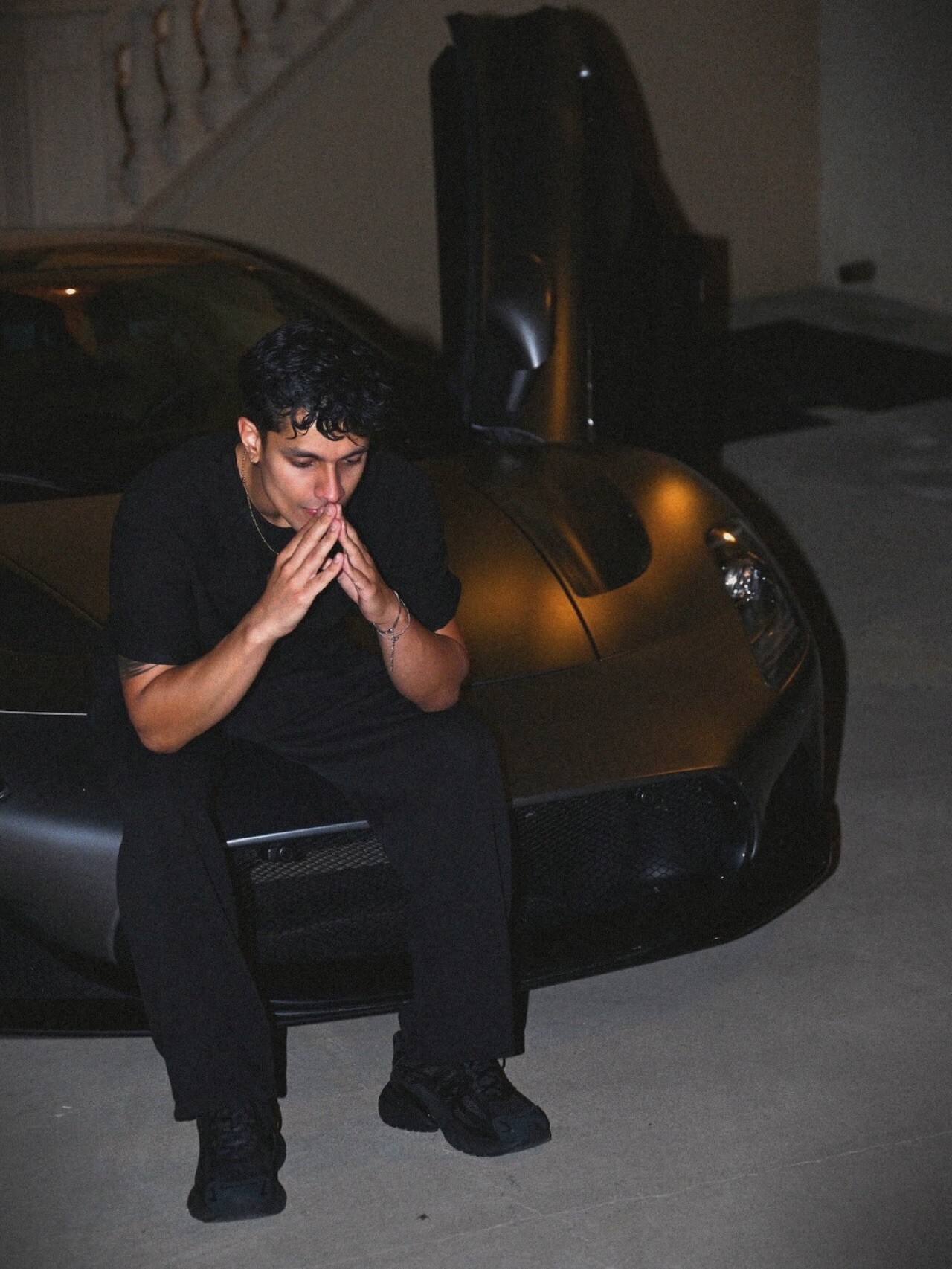 Aryan Mahajan standing with his hands together in front of a Maserati MC20