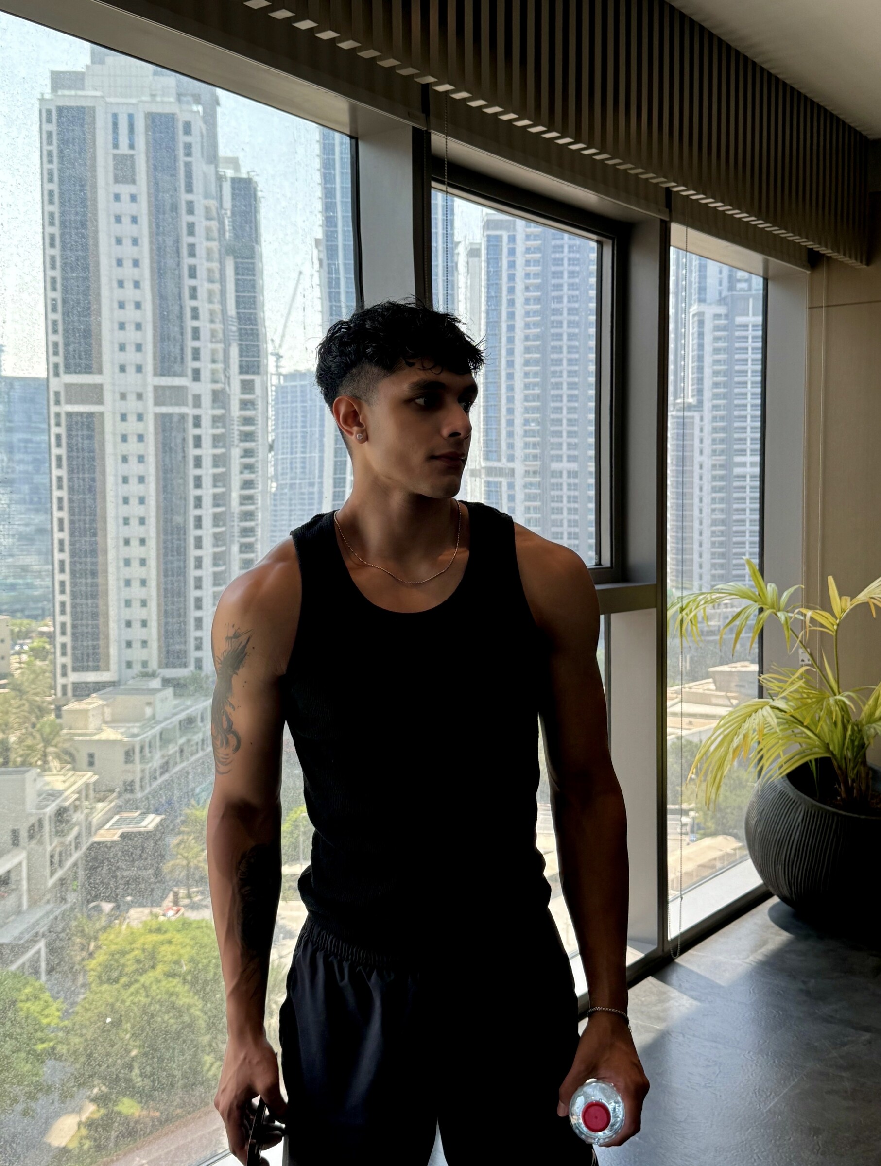 Aryan Mahajan wearing a black tank top in front of a city window