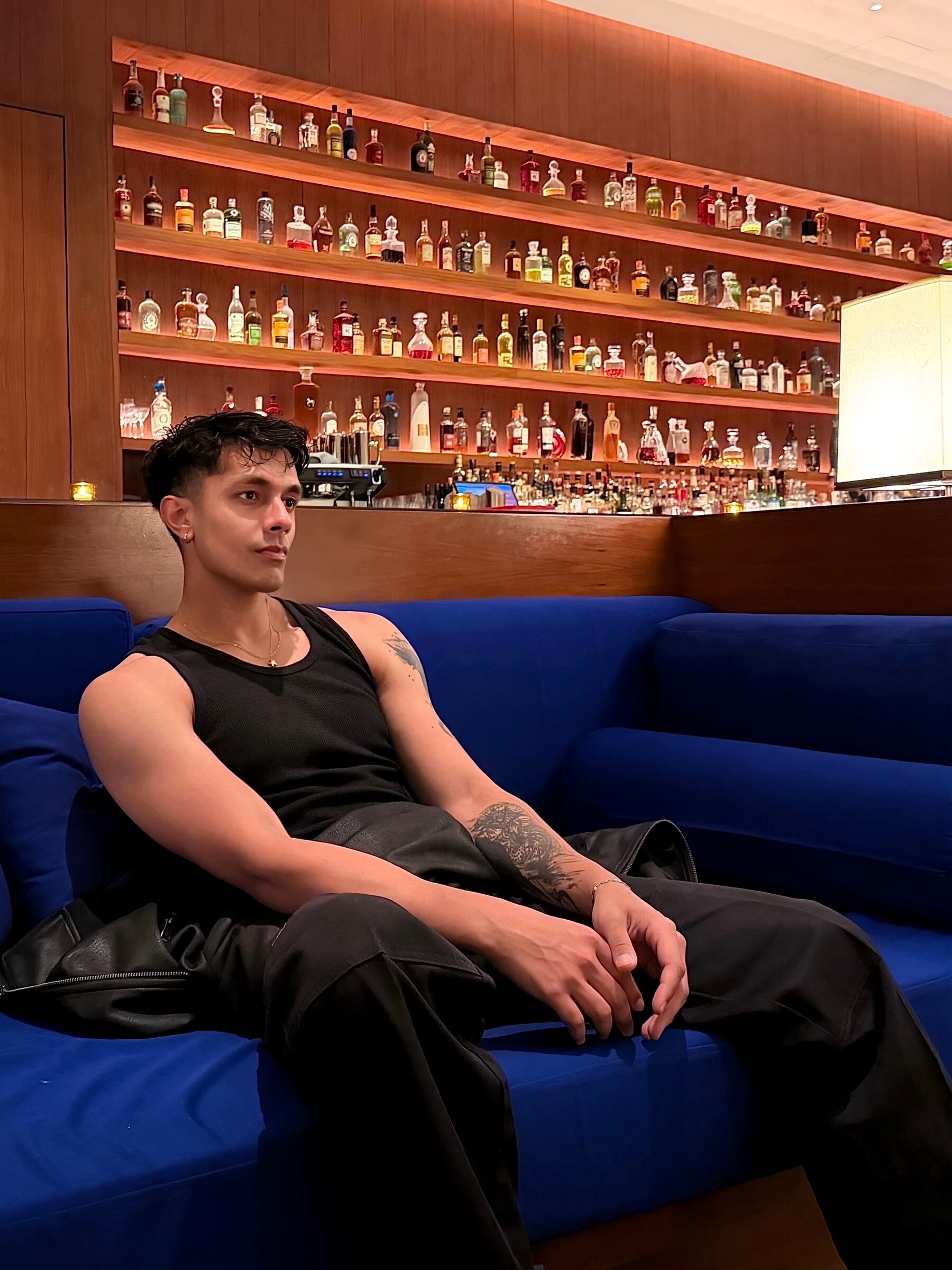 Aryan Mahajan wearing a black tank top while seated on a blue sofa