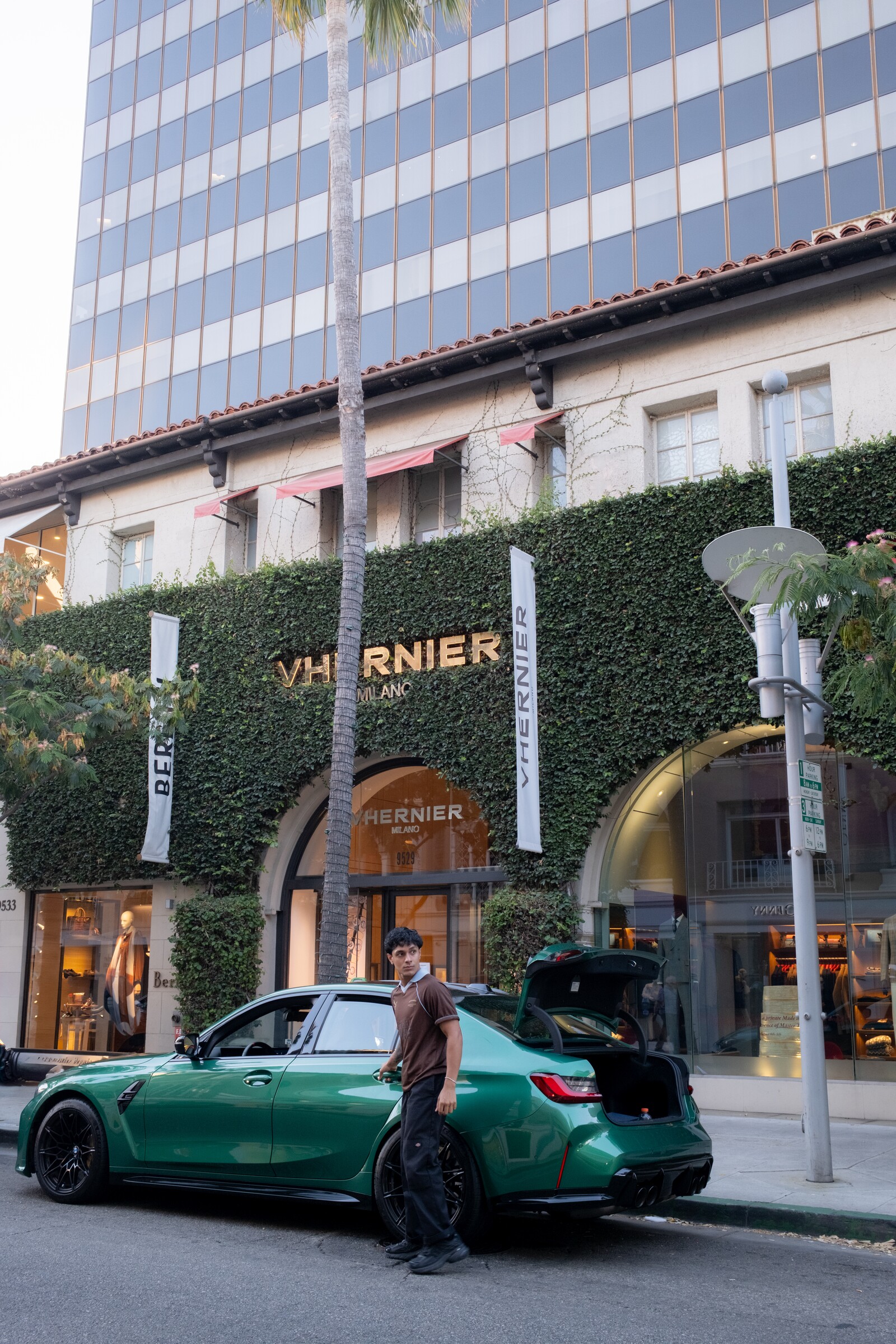 Aryan Mahajan wearing a brown jersey beside a green BMW M3 in Beverly Hills