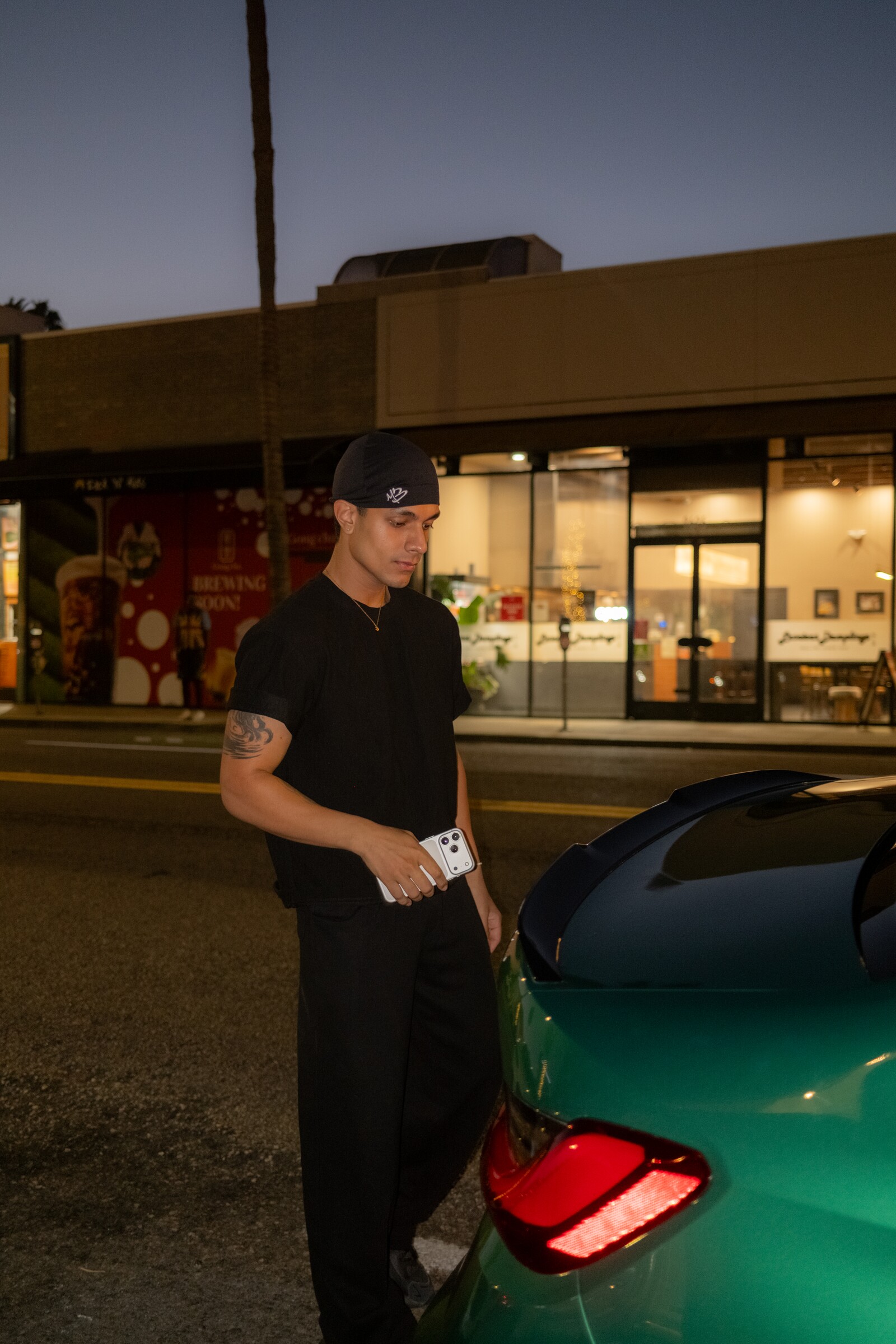 Aryan Mahajan in black beside a green BMW M3 at night