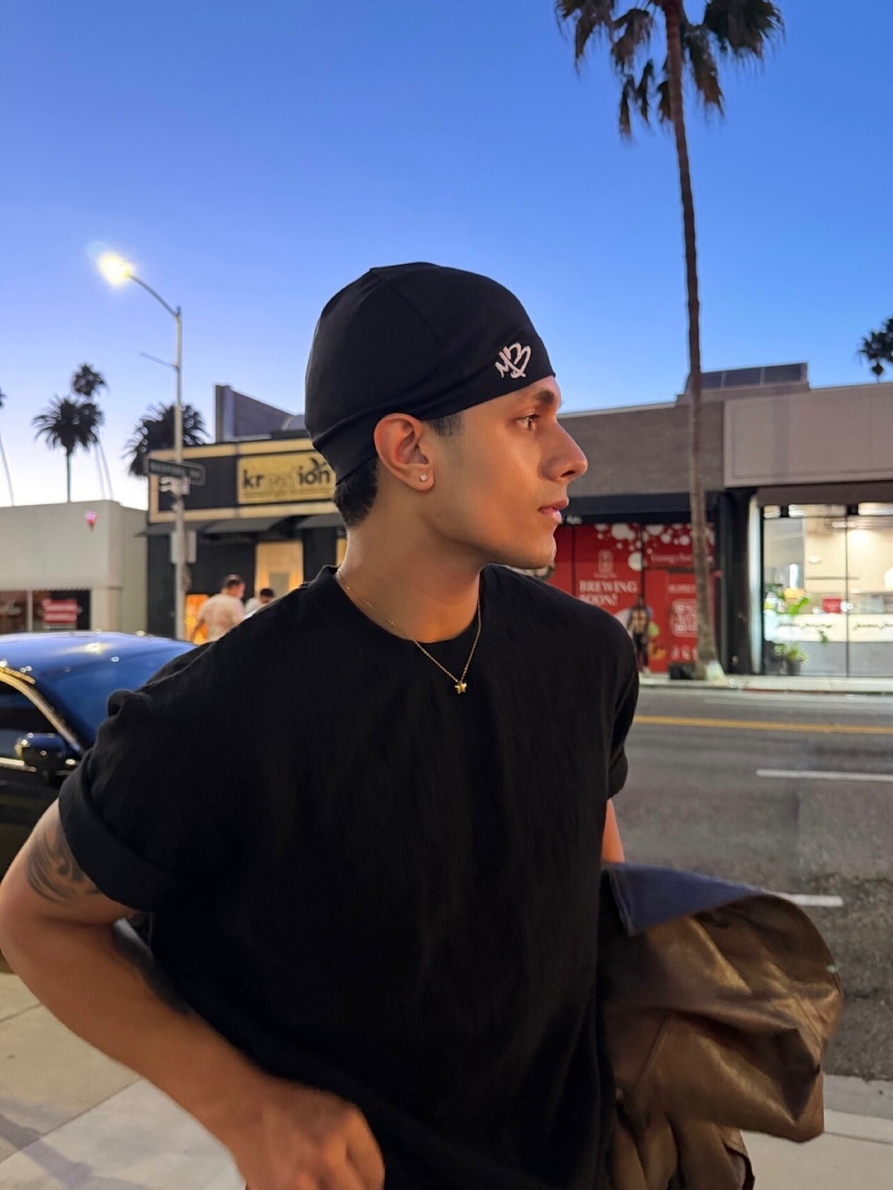 Aryan Mahajan wearing black and carrying a jacket on a Los Angeles street