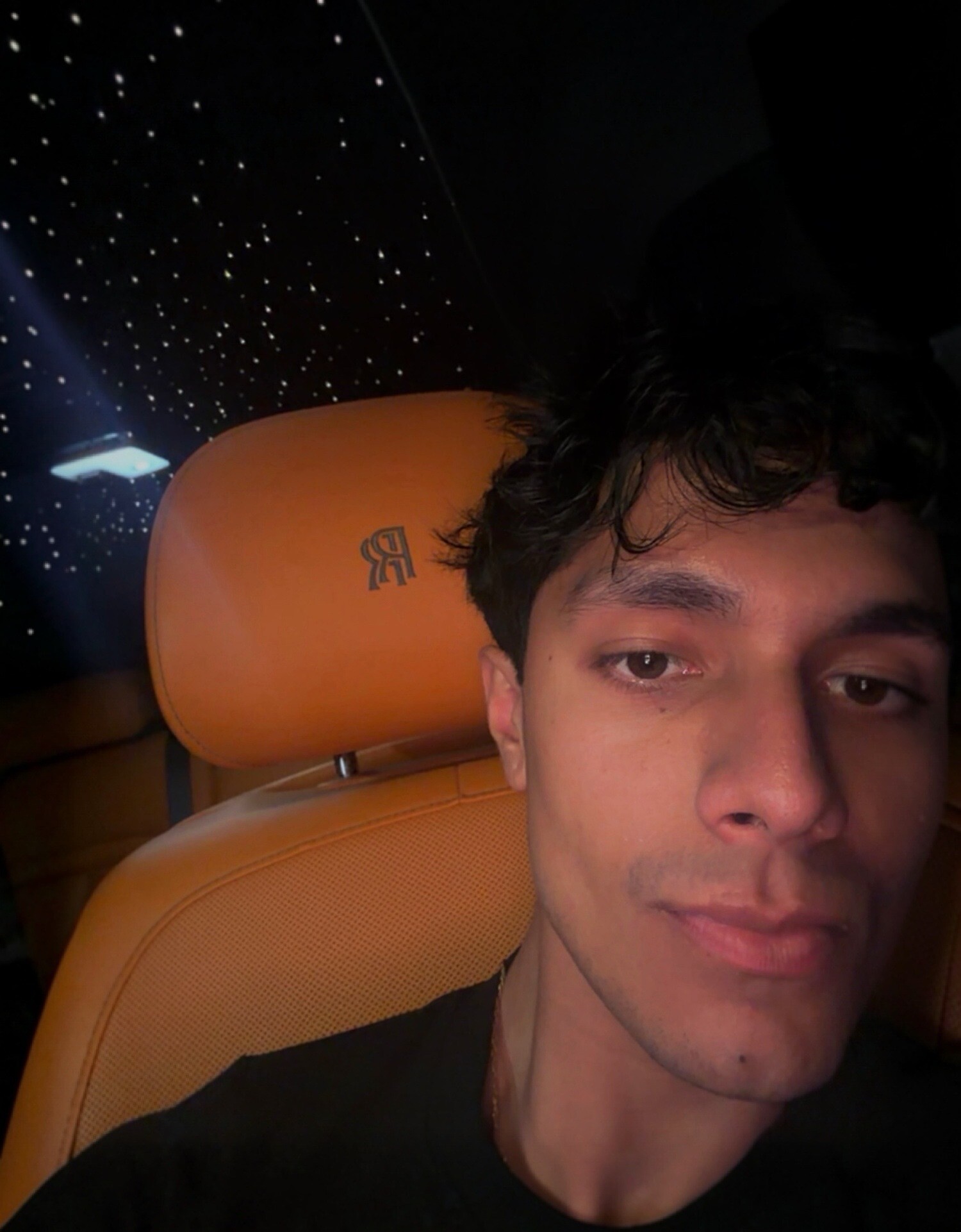 Aryan Mahajan taking a selfie inside a Rolls-Royce with orange leather seats